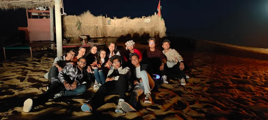 Eshan with friends sitting on sand at night during his undergrad years at GGS